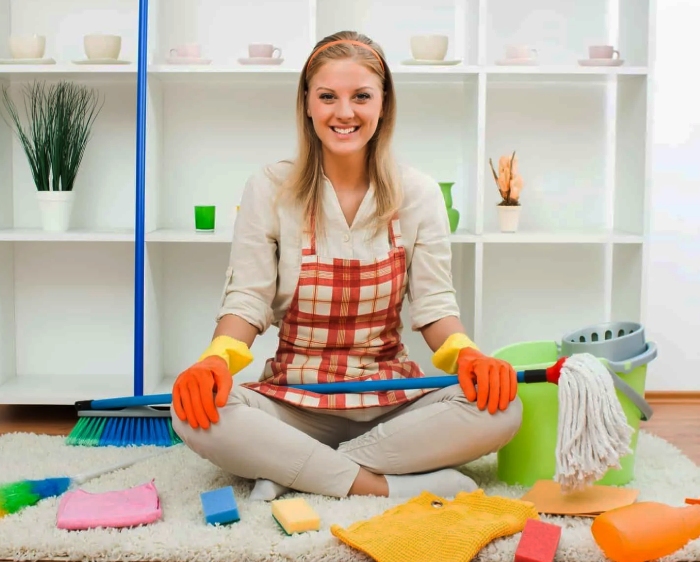 Smiling woman with "bond cleaning" supplies ready to work