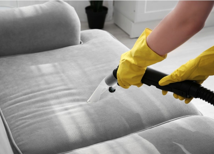 Handheld "couch steam cleaning" tool on a grey sofa