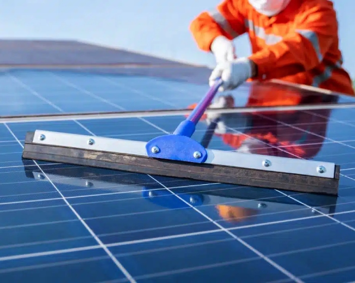Worker using squeegee for professional solar panel cleaning service
